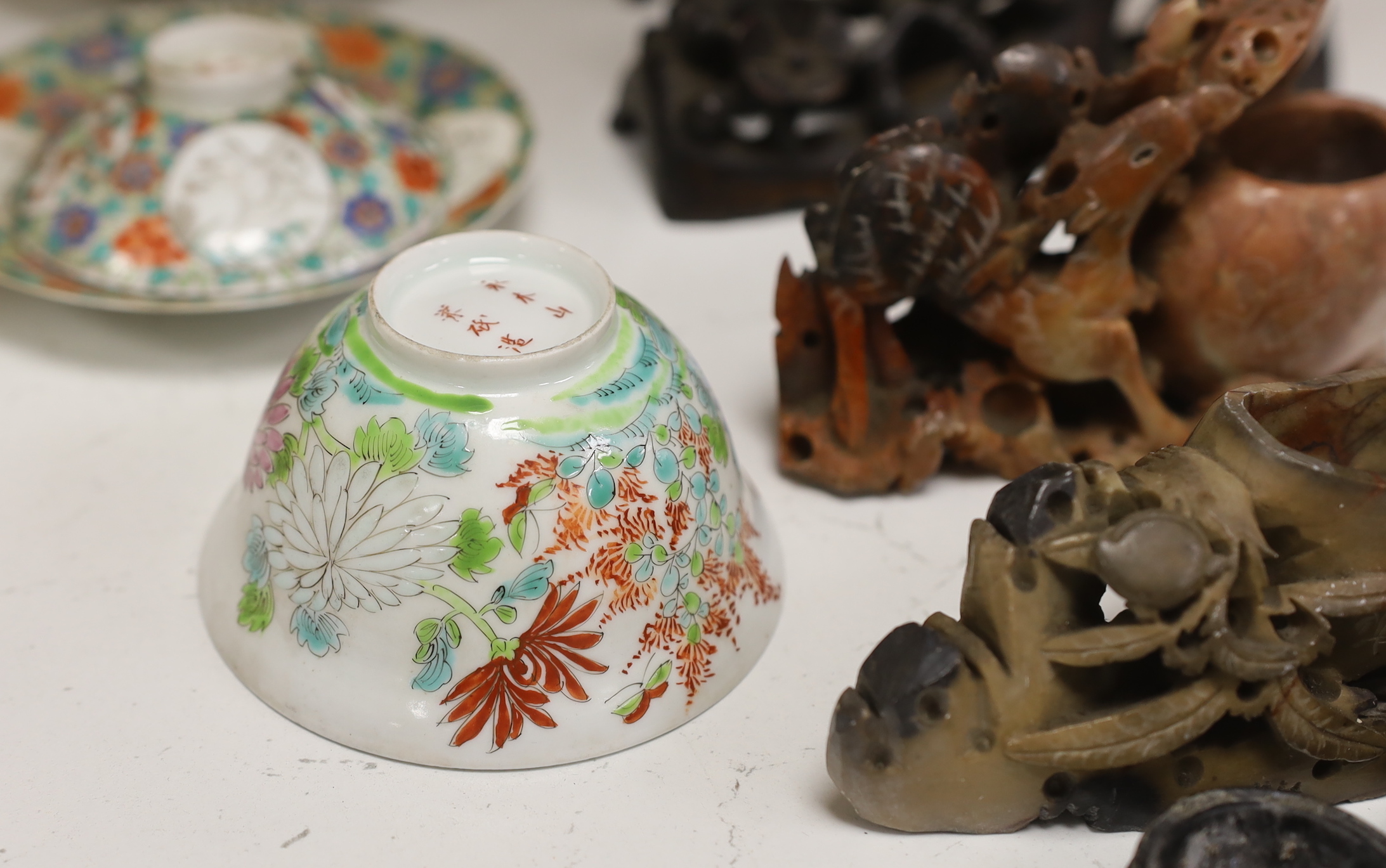 Two Japanese tea bowls one with cover and saucer, a saucer and cover, two Chinese soapstone carvings and four stands